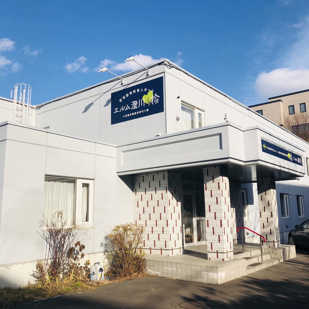 白を基調とした介護施設の建物外観。エントランスと施設名標識が確認できます。